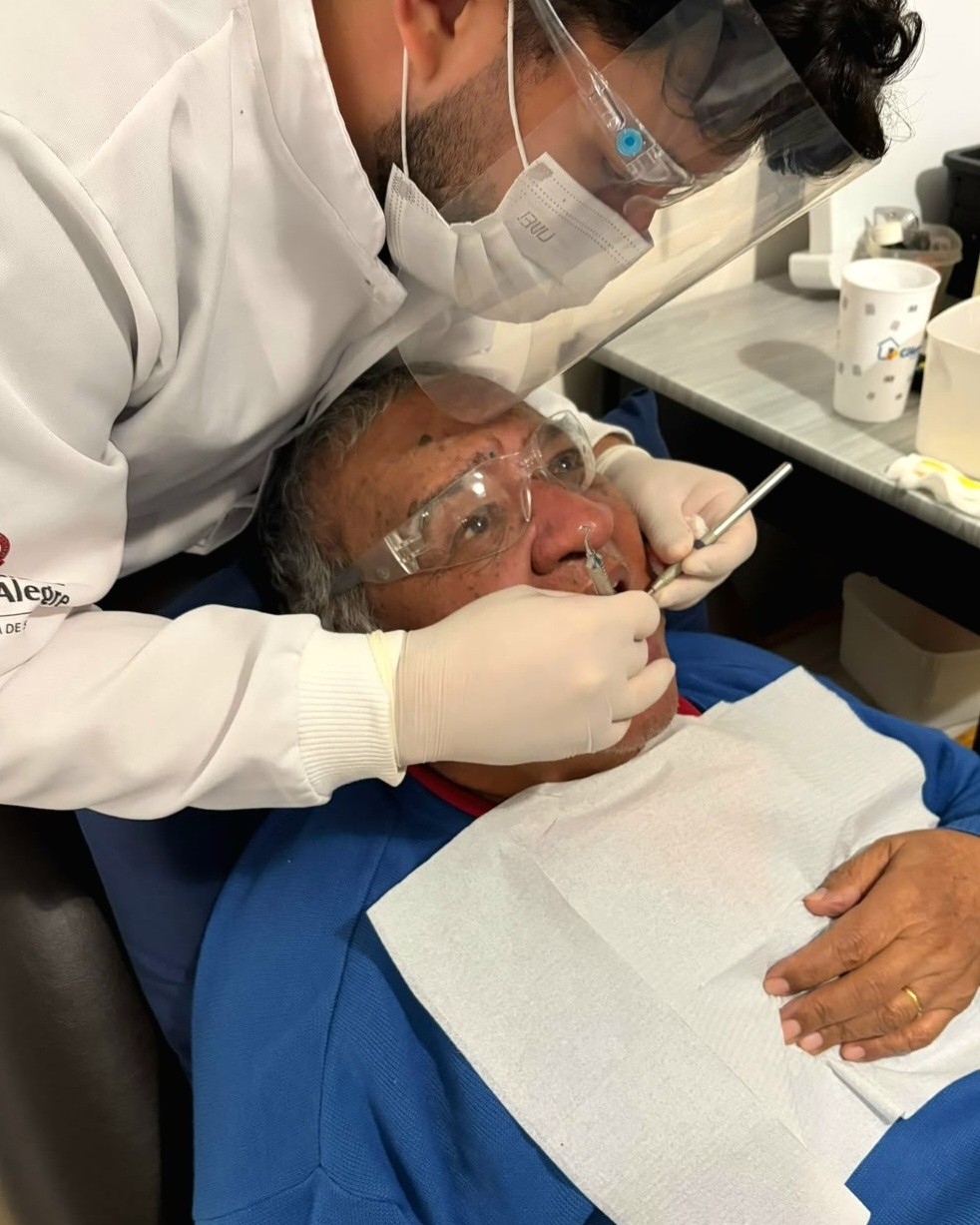 Profissional de odontologia atende um paciente em domicílio.